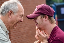 older man facing young man with Down Syndrome - smiling and laughing at each other