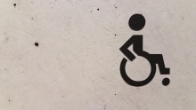concrete wall with affixed black 'wheelchair' symbol decal 