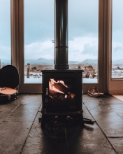 wood burning stove in room with windows and winter scene in background