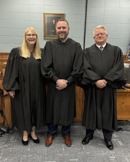 Judge Stephen Twiss presents Certificate of Appointment to Clerk Magistrate Aaron Benson alongside Judge Rachel Daugherty.