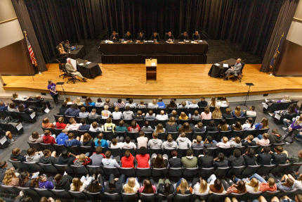 Balcony view of the supreme court about to hear arguments in front of an auditorium of students in Minden